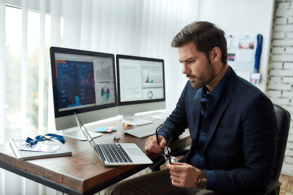 Person at desk looking at charts on monitors