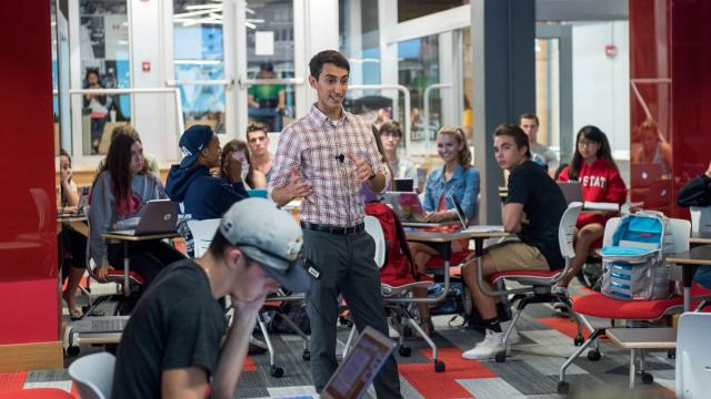 Instructor teaching in a classroom surrounded by students