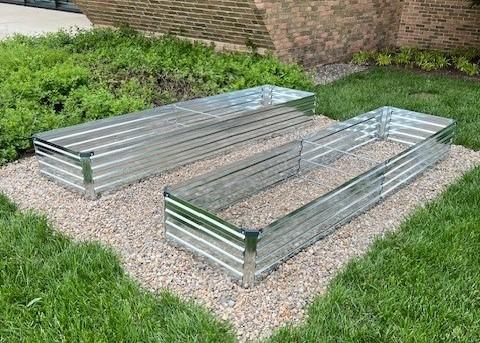 Two metal raised gardening beds on a gravel plot outside of Mount Hall.